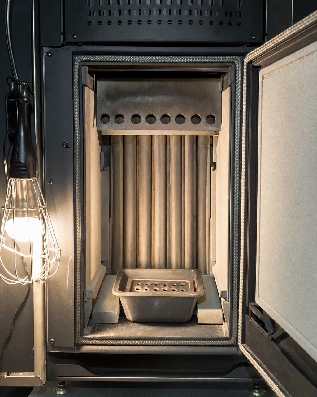 L’intérieur d’un foyer de poêle à granulés après nettoyage, creuset propre et tubes d’échangeur visibles