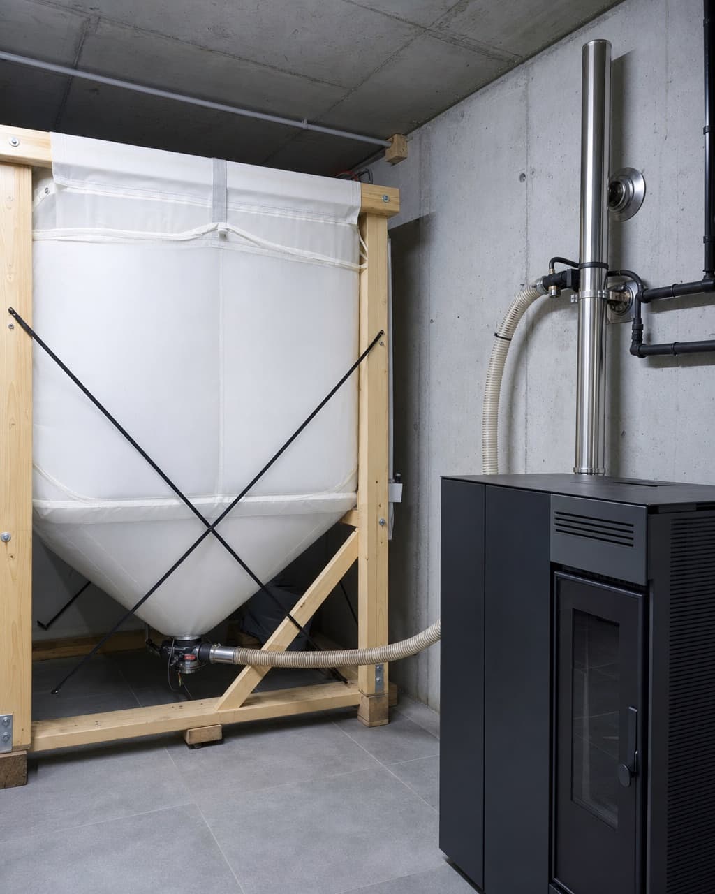 Un local technique avec un silo à granulés textile et sa vis d’alimentation vers le poêle