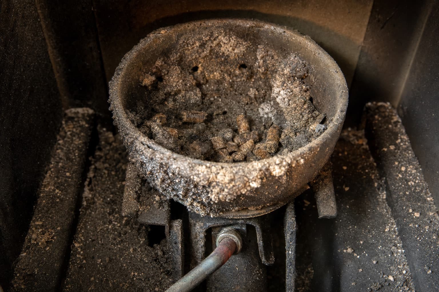 Un creuset couvert de mâchefer et de cendre agglomérée, encore en place au-dessus de la bougie d’allumage