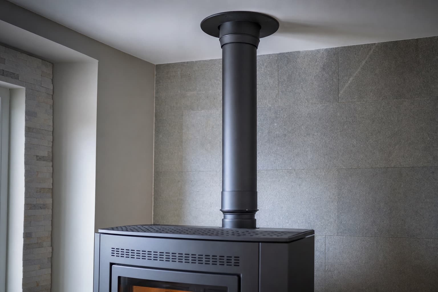Le conduit inox isolé qui monte derrière le poêle et traverse une plaque de plafond